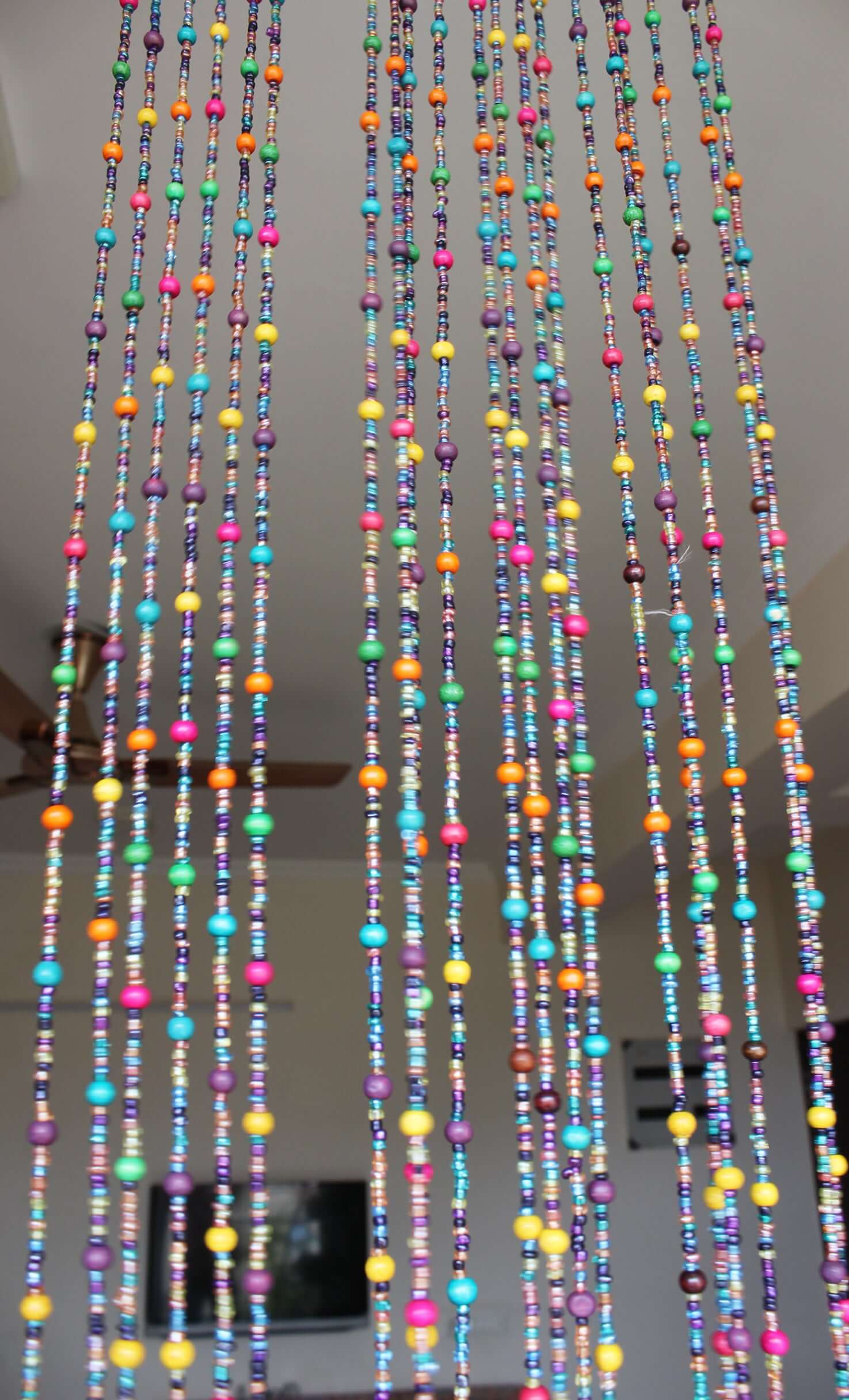 Handmade colorful glass bead strands with jingle bells—perfect for doorways or wall décor. Eco-friendly and crafted by women's artisans in India.